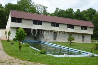 Salle décorée pour un événement avec tables dressées, chandeliers, nappes blanches et buffet garni en arrière-plan.