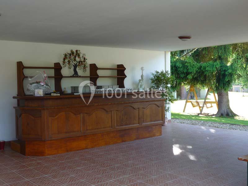 Comptoir en bois dans un espace ouvert avec carrelage au sol, étagères derrière et vue sur un jardin arboré.