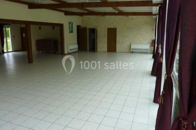 Salle décorée pour un événement avec tables dressées, chandeliers, nappes blanches et buffet garni en arrière-plan.