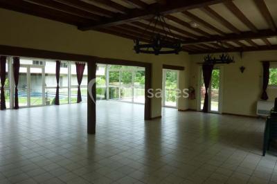 Salle décorée pour un événement avec tables dressées, chandeliers, nappes blanches et buffet garni en arrière-plan.