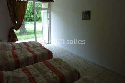 Salle décorée pour un événement avec tables dressées, chandeliers, nappes blanches et buffet garni en arrière-plan.