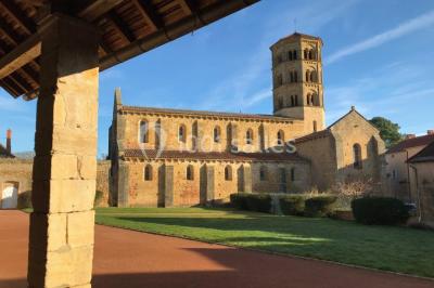 Église illuminée de nuit avec un clocher éclairé, vue depuis une allée avec des braseros allumés au premier plan.