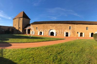 Église illuminée de nuit avec un clocher éclairé, vue depuis une allée avec des braseros allumés au premier plan.