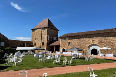 Église illuminée de nuit avec un clocher éclairé, vue depuis une allée avec des braseros allumés au premier plan.