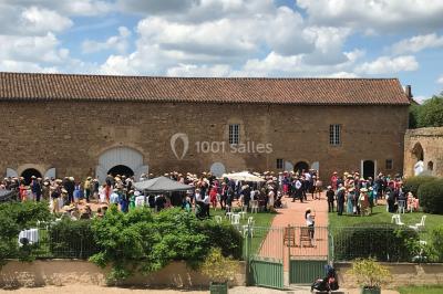 Église illuminée de nuit avec un clocher éclairé, vue depuis une allée avec des braseros allumés au premier plan.