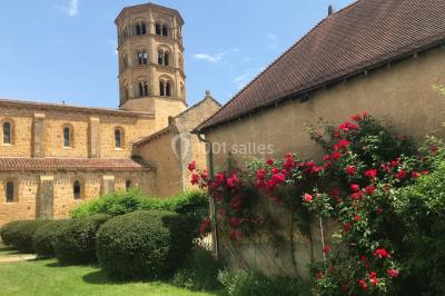 Église illuminée de nuit avec un clocher éclairé, vue depuis une allée avec des braseros allumés au premier plan.
