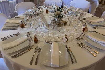 Église illuminée de nuit avec un clocher éclairé, vue depuis une allée avec des braseros allumés au premier plan.