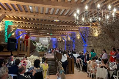 Église illuminée de nuit avec un clocher éclairé, vue depuis une allée avec des braseros allumés au premier plan.