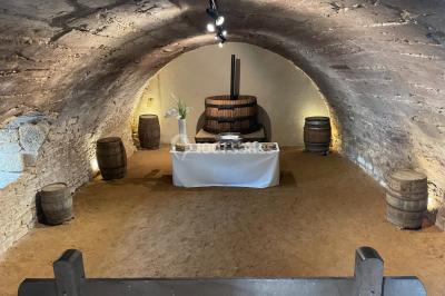 Église illuminée de nuit avec un clocher éclairé, vue depuis une allée avec des braseros allumés au premier plan.