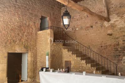 Église illuminée de nuit avec un clocher éclairé, vue depuis une allée avec des braseros allumés au premier plan.