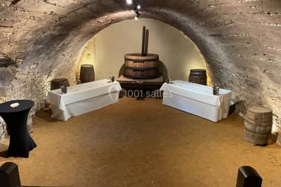 Église illuminée de nuit avec un clocher éclairé, vue depuis une allée avec des braseros allumés au premier plan.