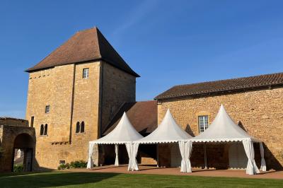 Église illuminée de nuit avec un clocher éclairé, vue depuis une allée avec des braseros allumés au premier plan.