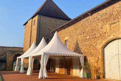 Église illuminée de nuit avec un clocher éclairé, vue depuis une allée avec des braseros allumés au premier plan.