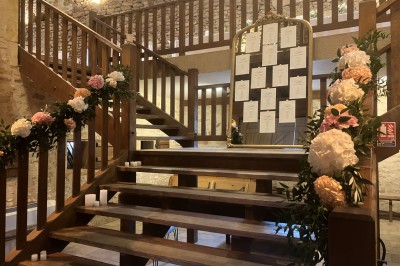 Église illuminée de nuit avec un clocher éclairé, vue depuis une allée avec des braseros allumés au premier plan.