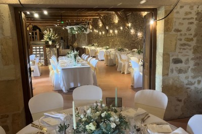 Église illuminée de nuit avec un clocher éclairé, vue depuis une allée avec des braseros allumés au premier plan.