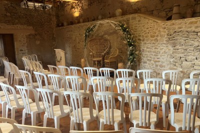 Église illuminée de nuit avec un clocher éclairé, vue depuis une allée avec des braseros allumés au premier plan.