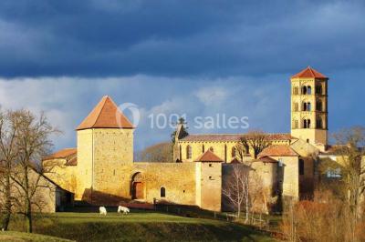 Église illuminée de nuit avec un clocher éclairé, vue depuis une allée avec des braseros allumés au premier plan.