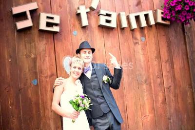 Lit double avec drap blanc, encadré par deux tables de chevet et lampes, dans une chambre au mur bleu et sol en bois.
