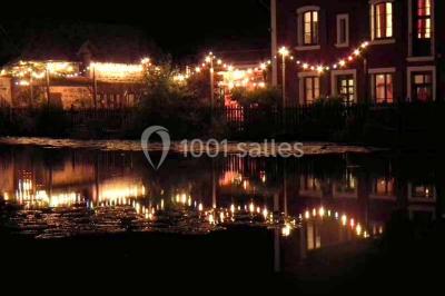 Lit double avec drap blanc, encadré par deux tables de chevet et lampes, dans une chambre au mur bleu et sol en bois.
