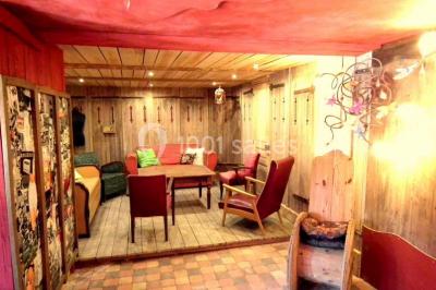 Lit double avec drap blanc, encadré par deux tables de chevet et lampes, dans une chambre au mur bleu et sol en bois.