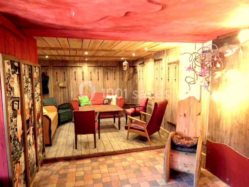 Espace intérieur chaleureux avec murs en bois, meubles rustiques, éclairage doux et sol en carreaux colorés.