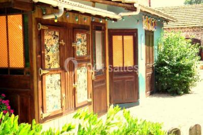 Lit double avec drap blanc, encadré par deux tables de chevet et lampes, dans une chambre au mur bleu et sol en bois.