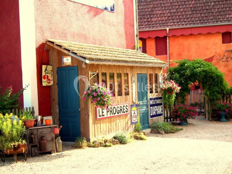 Façade d'une petite boutique en bois avec des fleurs suspendues, entourée de bâtiments colorés.