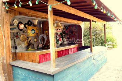 Lit double avec drap blanc, encadré par deux tables de chevet et lampes, dans une chambre au mur bleu et sol en bois.