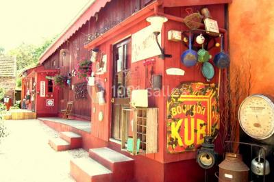 Lit double avec drap blanc, encadré par deux tables de chevet et lampes, dans une chambre au mur bleu et sol en bois.