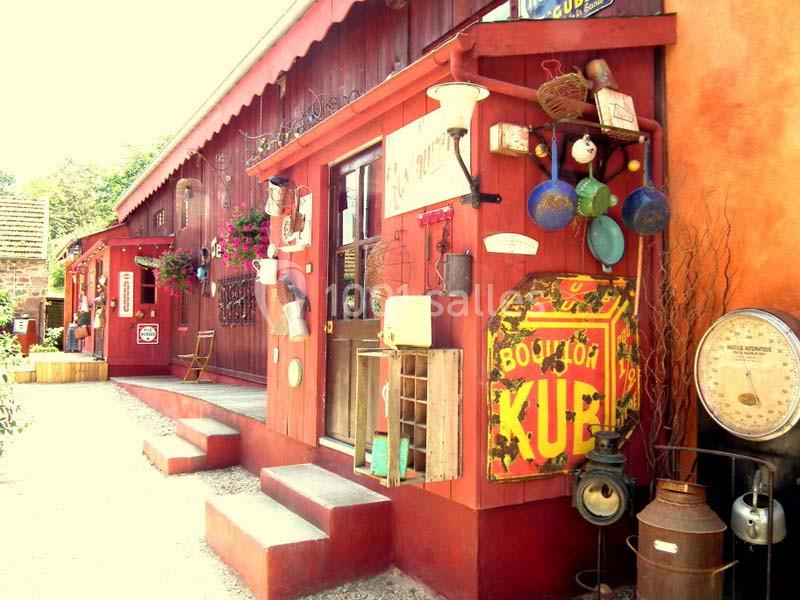 Façade d'une boutique vintage avec objets anciens, enseignes rétro et décoration colorée sur un mur rouge.
