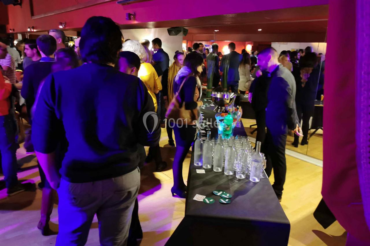 Personnes rassemblées dans une salle animée, discutant près d'une table avec des verres et des bouteilles.