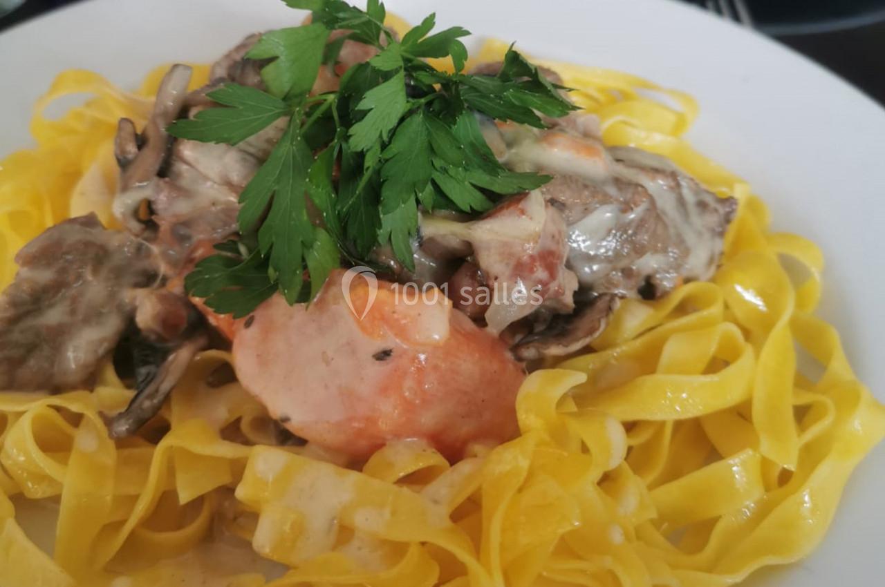 Assiette de tagliatelles fraîches garnies de sauce crémeuse aux champignons et décorée de persil frais.
