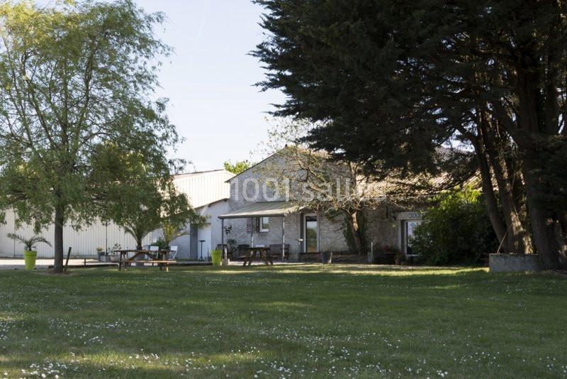 Vue d'un bâtiment entouré d'arbres et d'une pelouse avec des tables de pique-nique en bois.