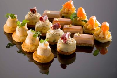 Plateau de bouchées apéritives variées comprenant légumes, foie gras, saumon fumé et feuilletés.