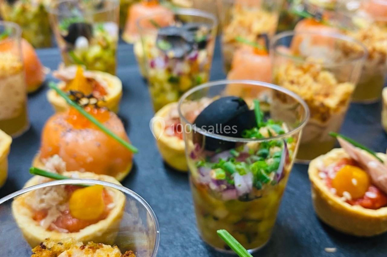 Assortiment de verrines et bouchées salées colorées disposées sur un plateau.