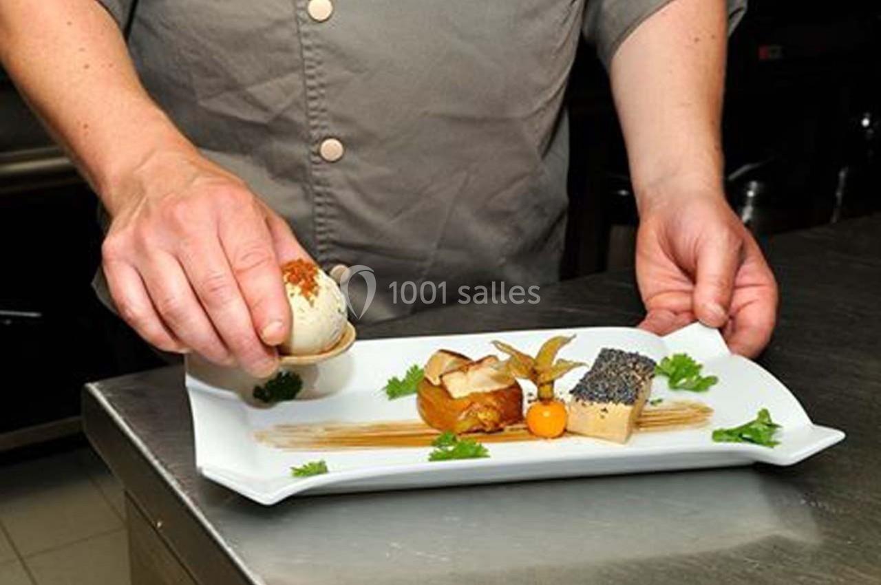 Un chef dispose soigneusement des éléments d'un plat gastronomique sur une assiette blanche.