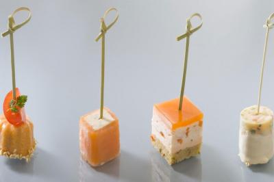 Assiette gastronomique avec viande, foie gras, cubes de fromage, sauce décorative et garniture verte.