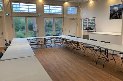 Façade en bois éclairée par des lumières violettes, avec une terrasse en bois et un grand parasol.
