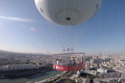 Façade en bois éclairée par des lumières violettes, avec une terrasse en bois et un grand parasol.