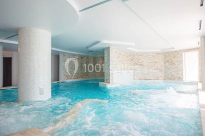 Terrasse ensoleillée avec tables hautes dressées, vue sur la mer et des arbres en arrière-plan.