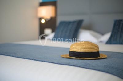 Terrasse ensoleillée avec tables hautes dressées, vue sur la mer et des arbres en arrière-plan.