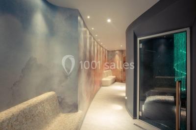 Terrasse ensoleillée avec tables hautes dressées, vue sur la mer et des arbres en arrière-plan.