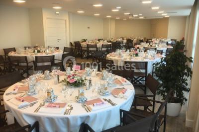 Terrasse ensoleillée avec tables hautes dressées, vue sur la mer et des arbres en arrière-plan.
