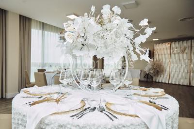 Terrasse ensoleillée avec tables hautes dressées, vue sur la mer et des arbres en arrière-plan.