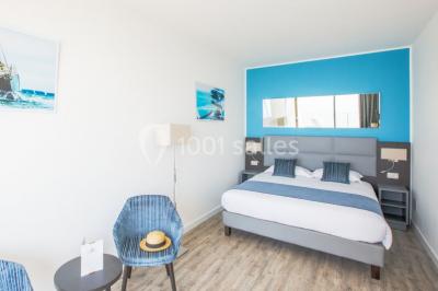 Salle de réunion lumineuse avec tables disposées en U, chaises blanches, bouteilles d'eau et écran de projection.