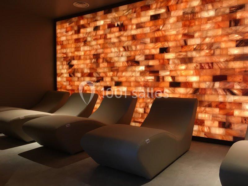 Fauteuils inclinés devant un mur rétroéclairé en briques de sel, dans une ambiance tamisée.