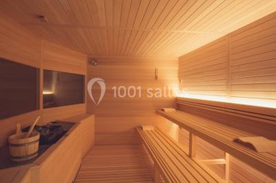 Salle de réunion lumineuse avec tables disposées en U, chaises blanches, bouteilles d'eau et écran de projection.