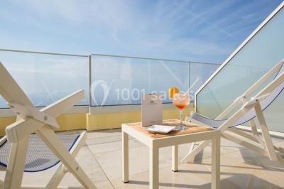 Salle de réunion lumineuse avec tables disposées en U, chaises blanches, bouteilles d'eau et écran de projection.