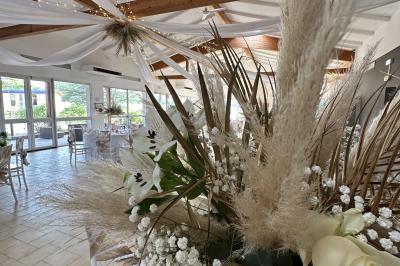 Table décorée avec des verres à pied, des fleurs roses et blanches, et des éléments de décoration en bois et dentelle.