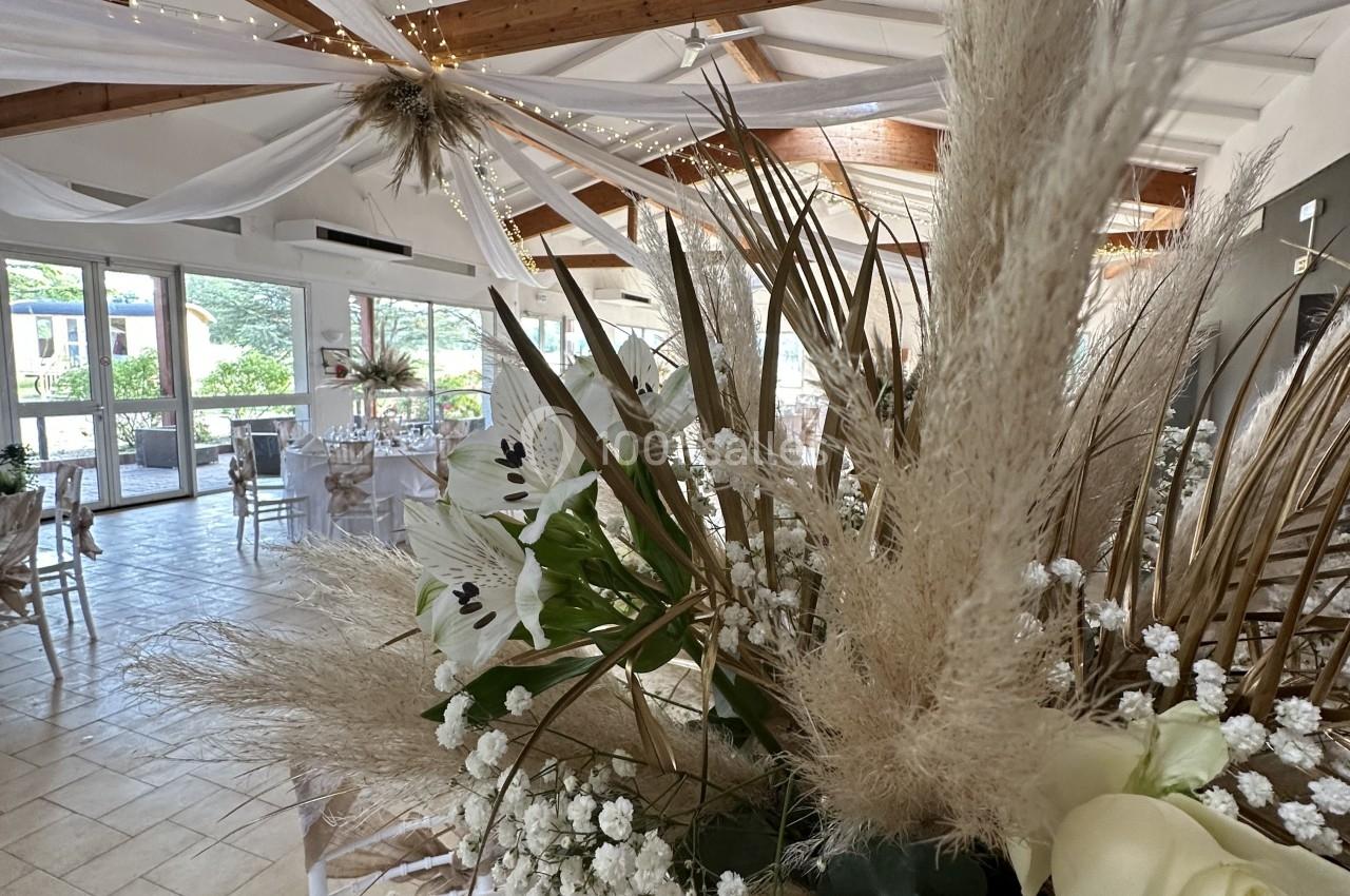 Décoration florale avec pampas, lys et gypsophile dans une salle lumineuse ornée de voilages et guirlandes.